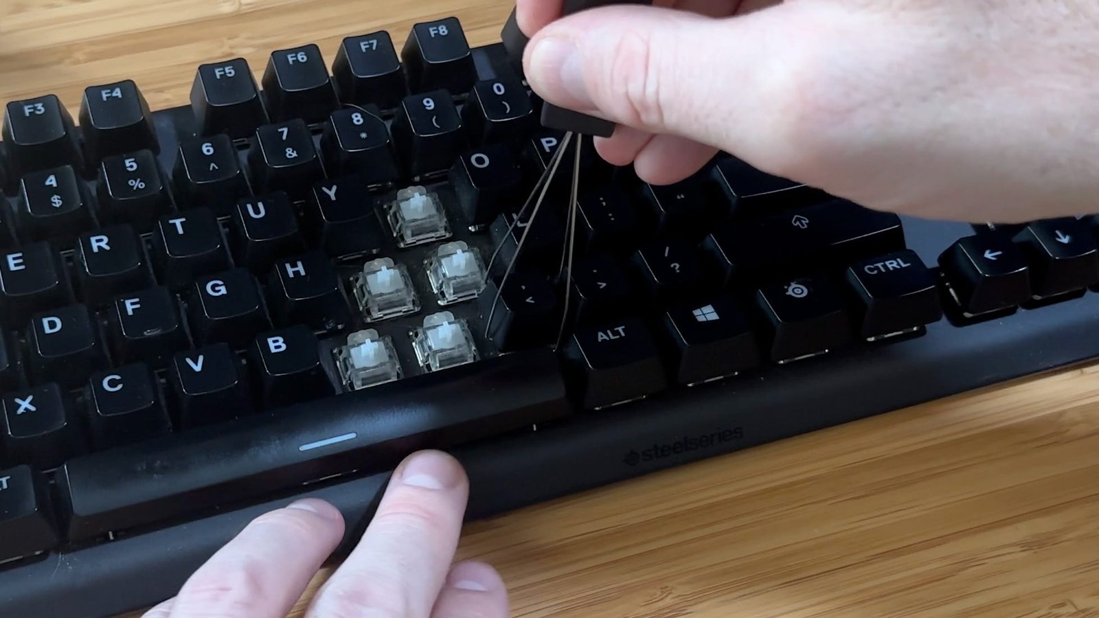 Keycap puller removing a mechanical keyboard keycap by pulling straight up