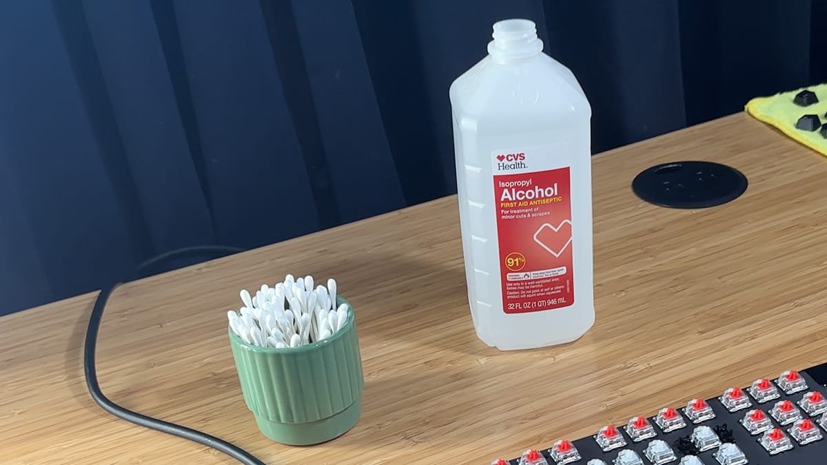 Close-up of a keyboard switch area being cleaned with a cotton swab to fix sticky keys